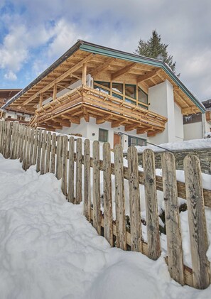A wooden house with a balcony, surrounded by a wooden fence and snow. - D-Town Lodge (Saalbach-Hinterglemm)
