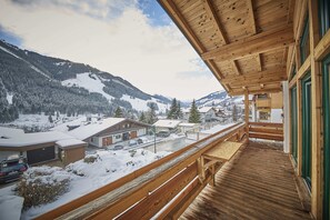 A wooden balcony overlooking a snowy mountain landscape with buildings and a road. - D-Town Lodge (Saalbach-Hinterglemm)