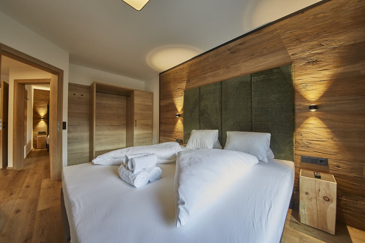 Una habitación de hotel moderna con una cama grande, cabecera de madera e iluminación empotrada.