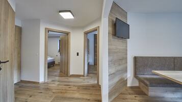 A modern interior with a wooden floor, a flat-screen TV mounted on a wall, and a bench.