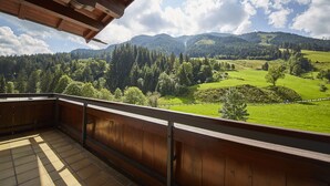 A wooden balcony with a view of a green landscape and mountains. - Appartements Gappmaier (Saalbach-Hinterglemm)