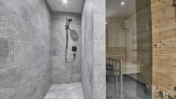 A modern bathroom with grey tiles, a glass shower enclosure, and wooden paneling.