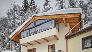 A two-story building with a balcony, wooden exterior, and snow-covered surroundings. - Holiday Lodge Central (Saalbach-Hinterglemm)