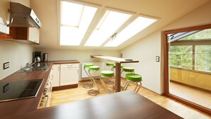 A modern kitchen with a skylight, wooden flooring, and green bar stools. - Holiday Lodge Central (Saalbach-Hinterglemm)