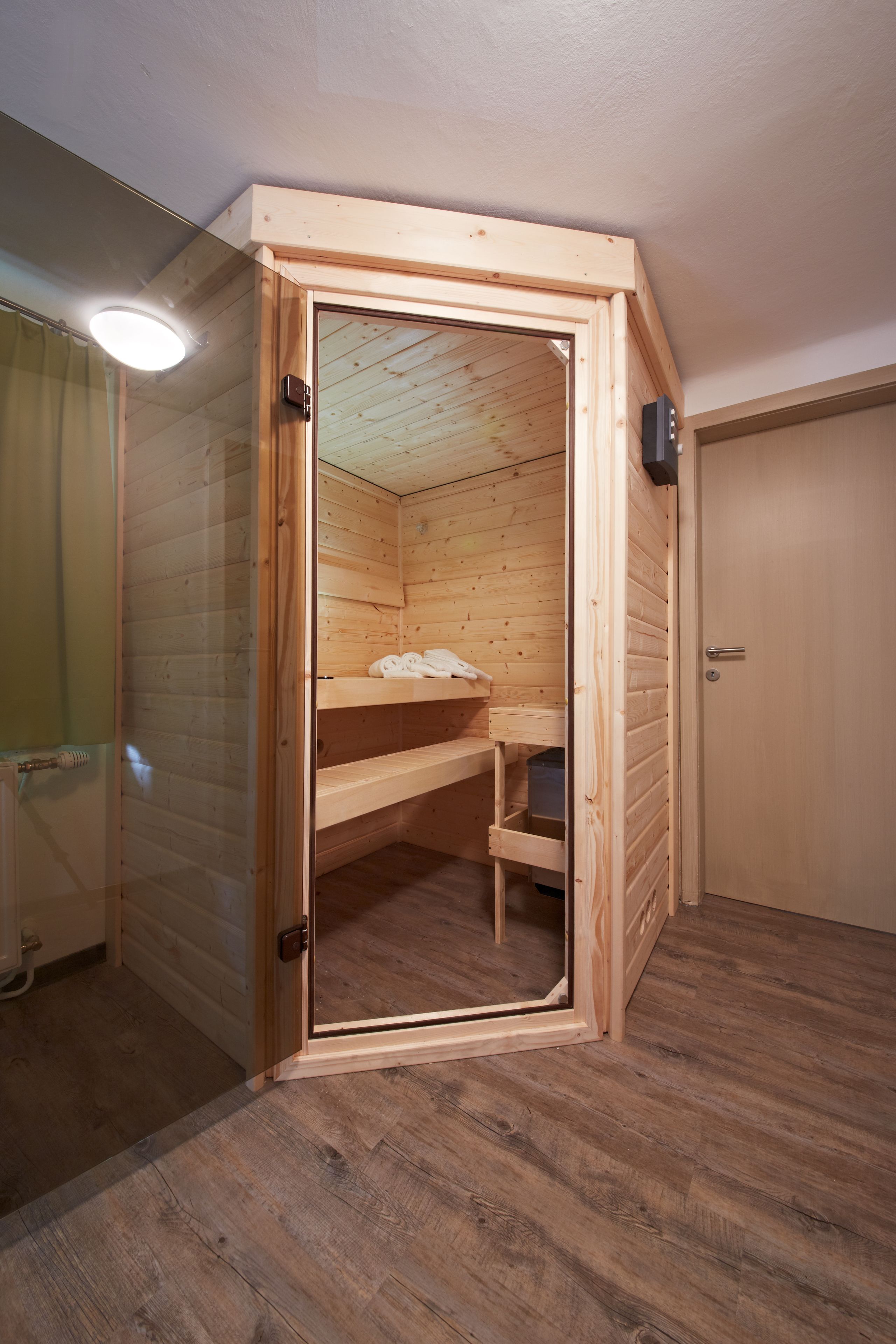 Un sauna en bois, avec un banc, des étagères, une porte et un porte-serviettes visible.