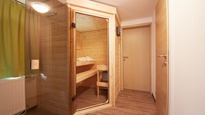 A wooden room with a built-in bench and a door leading to another room. - Holiday Lodge Central (Saalbach-Hinterglemm)