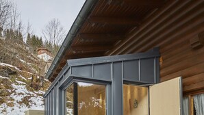 A modern cabin with a large window, a wooden door, and a small porch. - FIVE SEASONS | Hideaway Saalbach (Saalbach-Hinterglemm)
