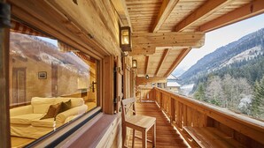 Una cabaña de madera con balcón, paredes de madera y vistas a un paisaje montañoso.