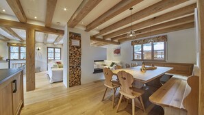 Un interior de madera con zona de comedor, sofá y chimenea.
