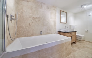 A modern bathroom with a large bathtub, a shower, and a vanity with a mirror. -  Chalet Tannenbaum (Saalbach-Hinterglemm)