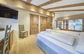 A bedroom with a bed, wooden wardrobe, and a desk with a chair. -  Chalet Tannenbaum (Saalbach-Hinterglemm)