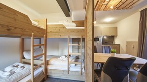 A compact room with bunk beds, a dining table, and a kitchen area. - Time for Sport Appartements (Saalbach-Hinterglemm)