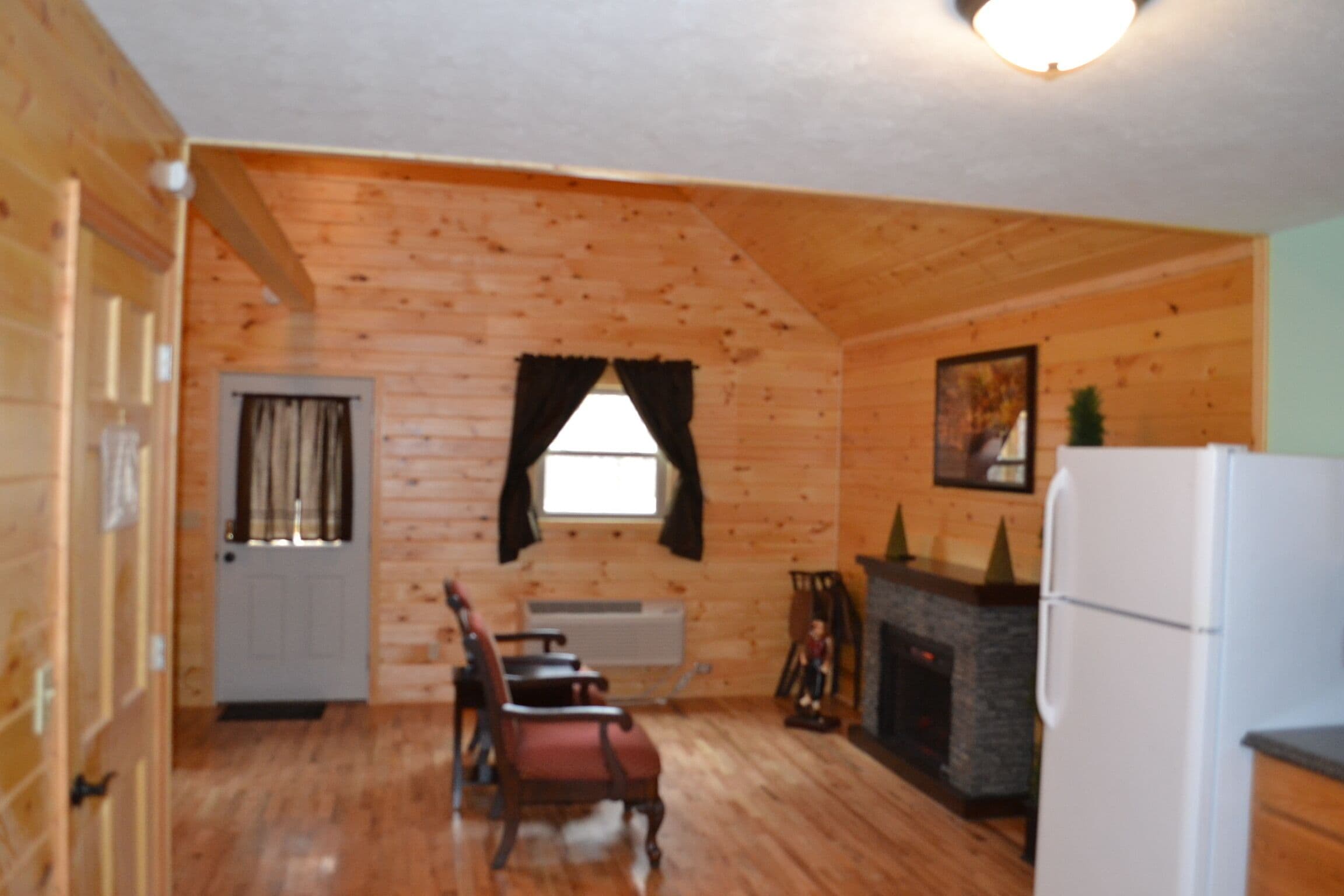 Ein rustikales Blockhaus-Interieur mit Essbereich, Kamin und Kühlschrank.