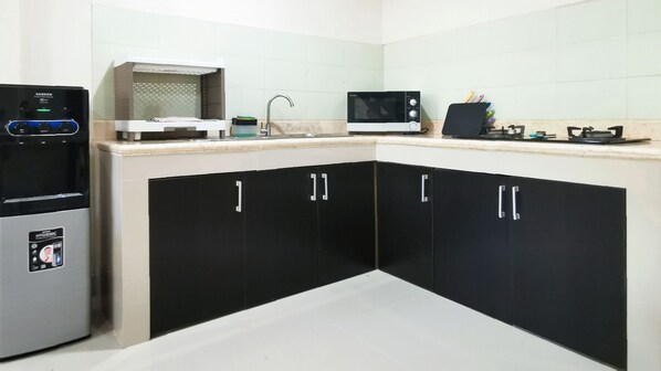 Una cocina con gabinetes negros, un refrigerador de acero inoxidable, un microondas y una estufa a gas.