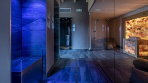 A modern lobby with a blue-lit wall, a reception area with a stone wall, and a wooden ceiling. - Cobue Wine Resort & SPA (Pozzolengo)