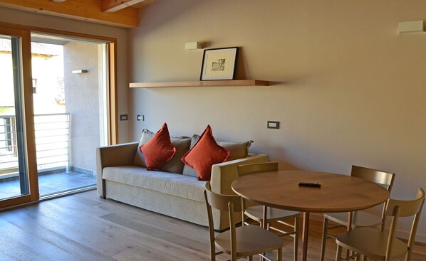 A living room with a sofa, two red pillows, a wooden coffee table, and four chairs. - Cobue Wine Resort & SPA (Pozzolengo)
