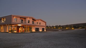Un edificio moderno con techo plano y grandes ventanales, rodeado por un camino de grava.