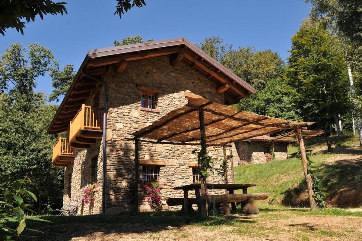 Une maison de campagne en pierre, dotée d’un balcon en bois et d’un patio couvert.