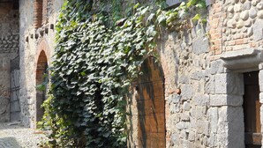 Un vieux bâtiment en pierre dont les murs sont recouverts de lierre, une rue pavée et une allure rustique.