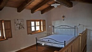 Une chambre avec un plafond en bois, un cadre de lit en métal et une balustrade en bois.