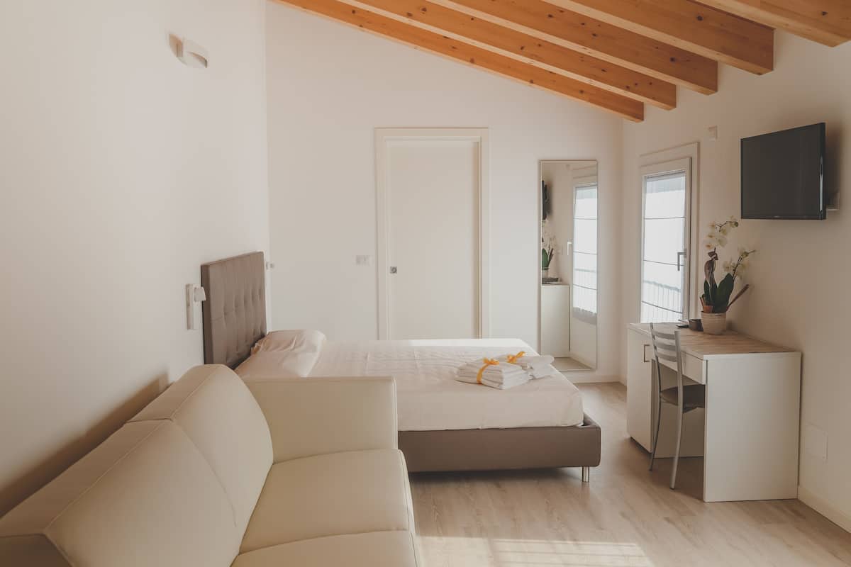 A bedroom with a bed, a desk, and a TV.