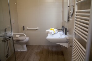 A modern bathroom with a toilet, sink, and glass shower enclosure. - Terra Ferma Rooms & More (Salzano)