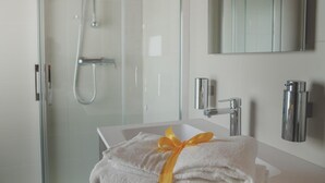 A modern bathroom with a glass shower enclosure, a white sink, and a mirror above it. - Terra Ferma Rooms & More (Salzano)