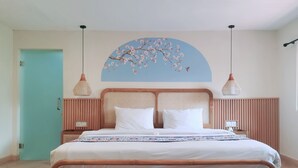 Un dormitorio ordenado con cama, mesitas de noche y una obra de arte colgada en la pared.