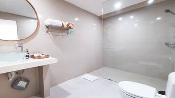A modern bathroom with a glass-enclosed shower, a white sink with a mirror, and a toilet.