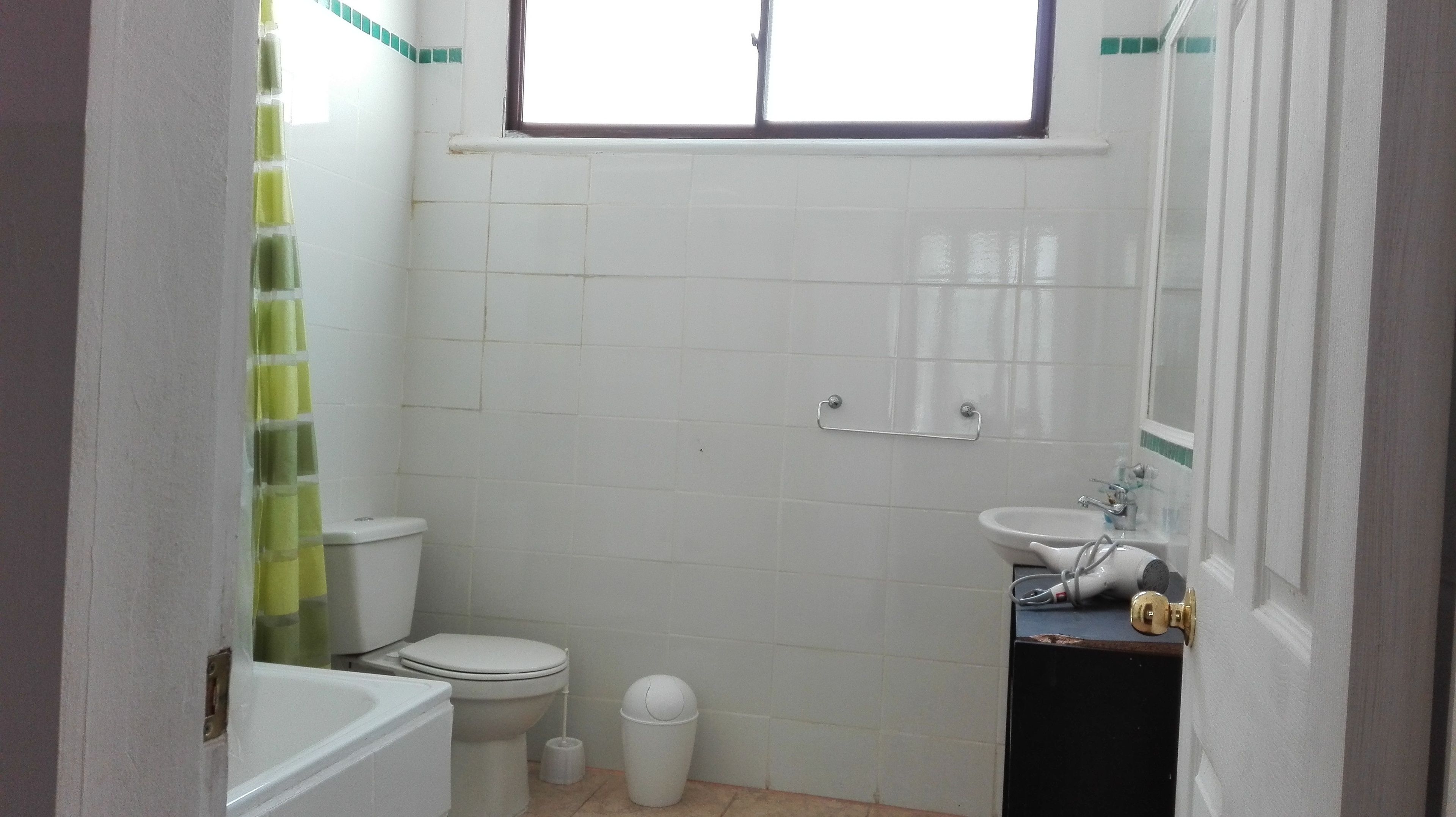 Et lille, rent badeværelse med toilet, håndvask og badekar.