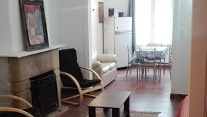 Een woonkamer met een open haard, een bank, een salontafel en een eethoek met stoelen en een tafel.