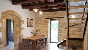 A rustic interior with a wooden dining table, stone walls, and a spiral staircase. - Traditional Villa in Fres (Apokoronas)