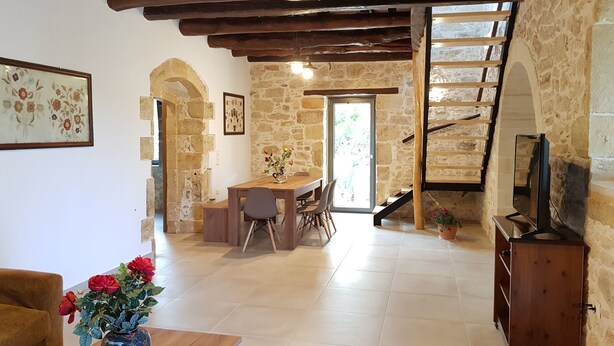 A rustic interior with exposed wooden beams, stone walls, a dining area, and a staircase. - Traditional Villa in Fres (Apokoronas)