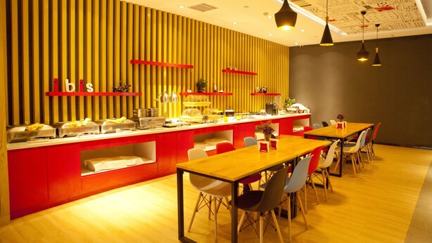 Un comedor moderno con piso de madera, mobiliario rojo y blanco, y una pared con listones de madera verticales y estantes rojos.