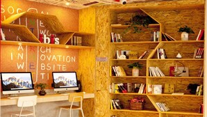 Un espacio de trabajo acogedor con dos escritorios, sillas y una estantería llena de libros y objetos decorativos.