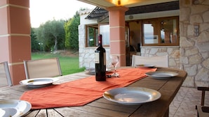 Une table en bois, dressée pour le repas, avec des assiettes, une bouteille de vin et des verres.