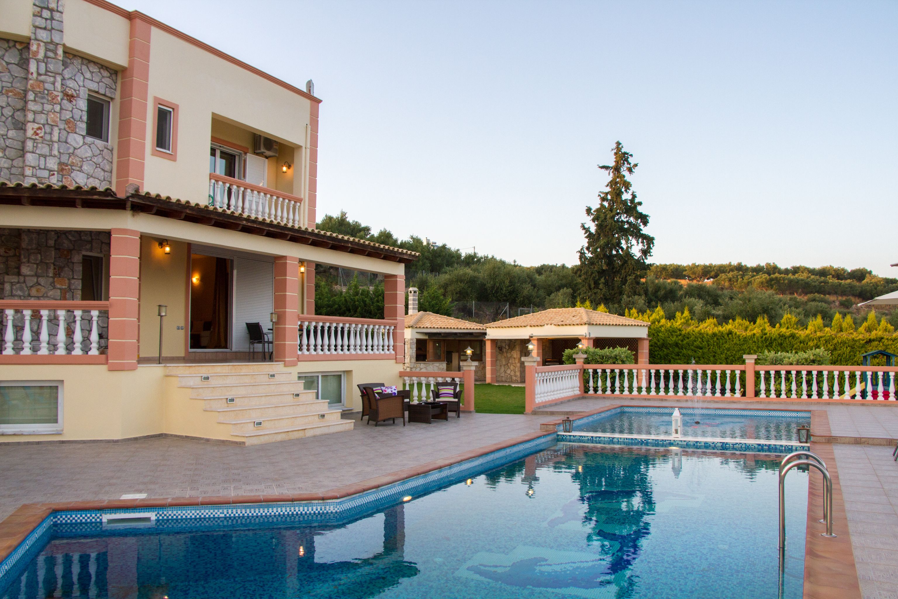 A poolside area with a stone building, outdoor seating, and a clear view of the surrounding landscape.