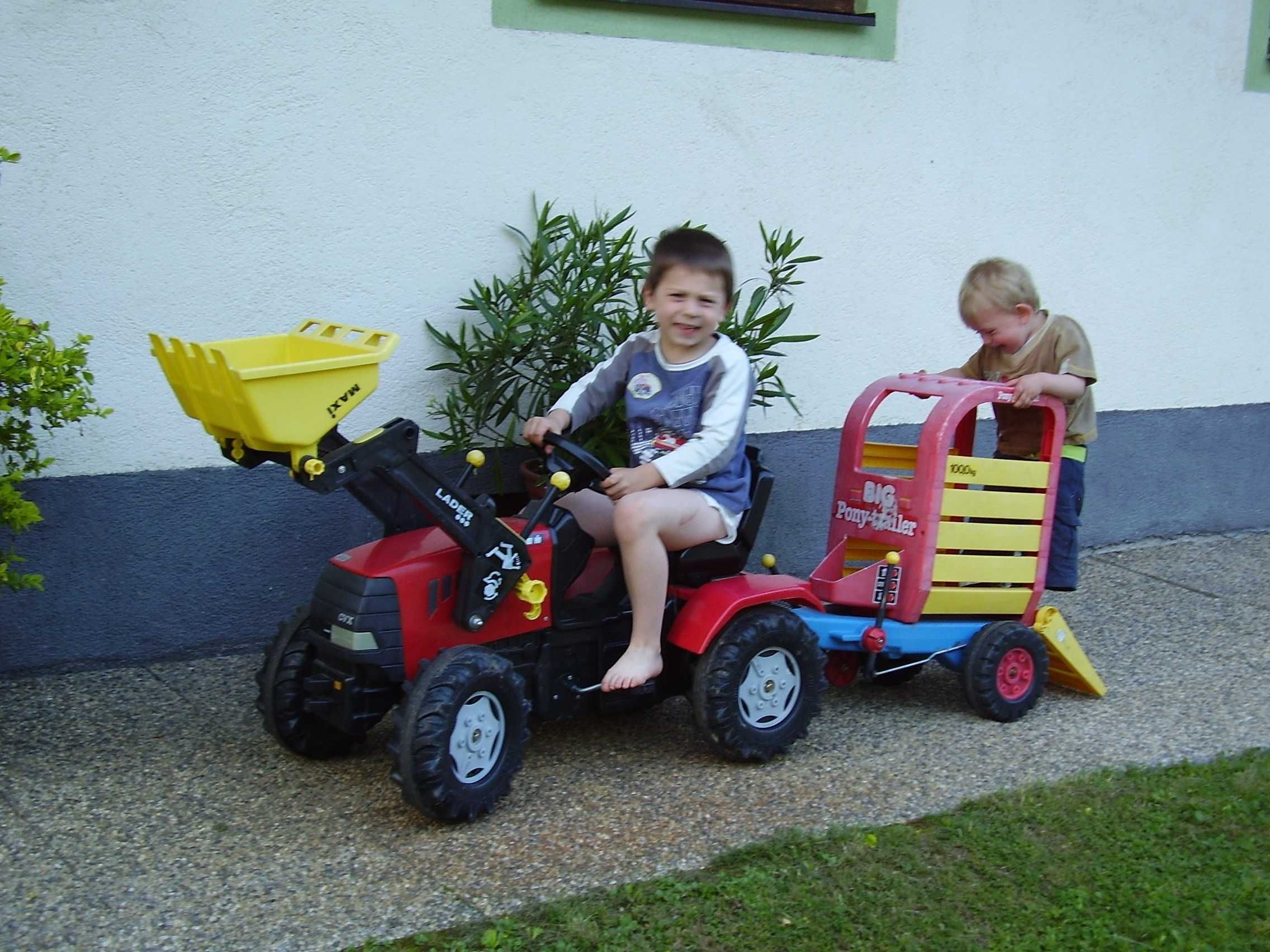 Two children on toy tractors in front of a building.