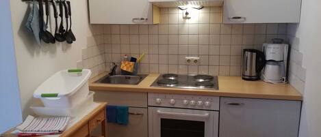 A compact kitchen with a sink, stove, oven, and a coffee maker.