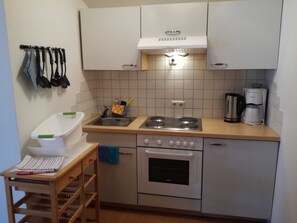 Una cocina compacta con un lavamanos, estufa, horno y cafetera.