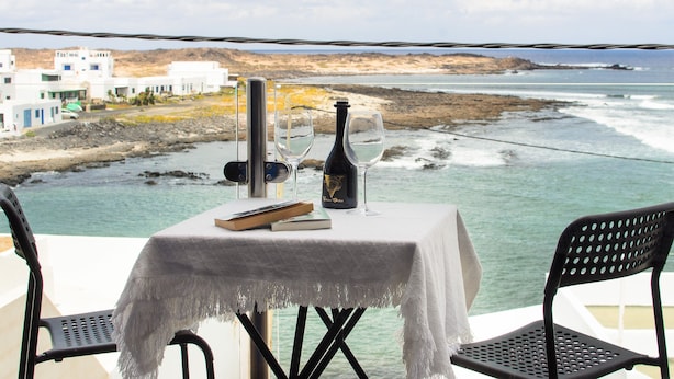 Una mesa con una botella y vasos, con vista al mar.