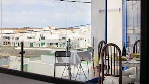 Un balcón con una mesa lista para comer, sillas y vistas a edificios.