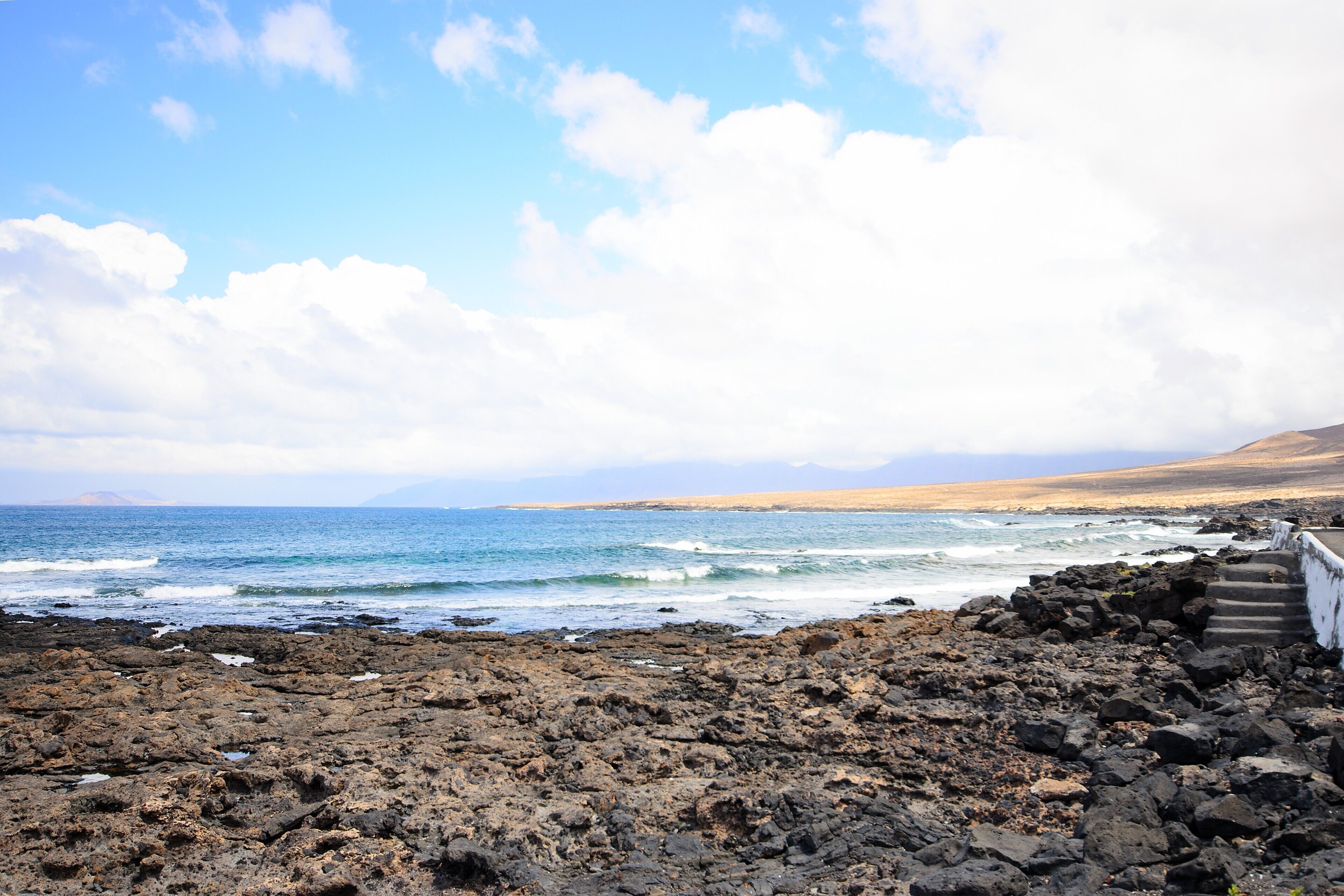 A rocky coastal landscape with a clear sky and ocean.