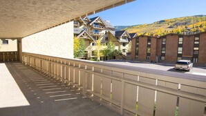 A hotel with a covered outdoor area, a parking lot, and a view of a mountainous landscape with autumn foliage. - Scorpio #104 2 Bedroom Condo by RedAwning (Vail)
