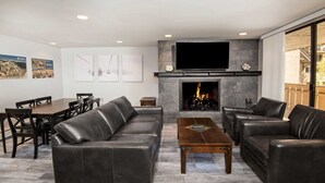 A modern living room with a fireplace, leather sofas, a dining table, and artwork on the walls. - Scorpio #104 2 Bedroom Condo by RedAwning (Vail)