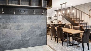 A modern kitchen with dark tiles, a wooden countertop, and a dining area with a long table and chairs.