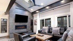 A modern living room with a stone fireplace, leather sofa, and a flat-screen TV.