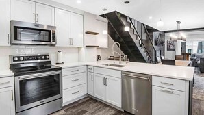 A modern kitchen with stainless steel appliances, white cabinetry, and a central island.
