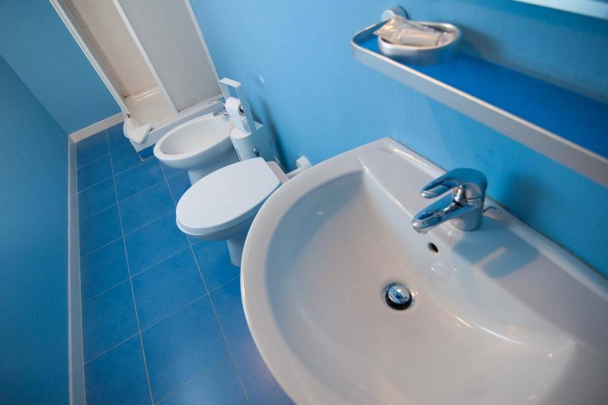 A bathroom with a white sink, a toilet, and a bidet.