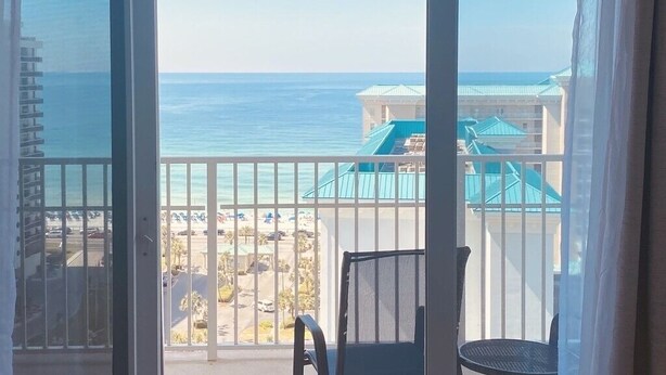 A balcony with a view of the ocean and a resort area. - Destin Miramar Sweeping Ocean Views ~ Five Swimming Pools ~ Relaxing! End Unit.  (Destin)